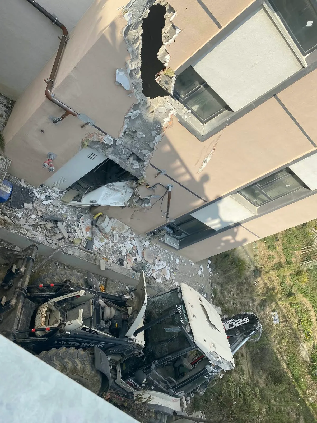 Antakya'da iş makinesi TOKİ binasına çarpıp devrildi, operatör hafif yaralandı